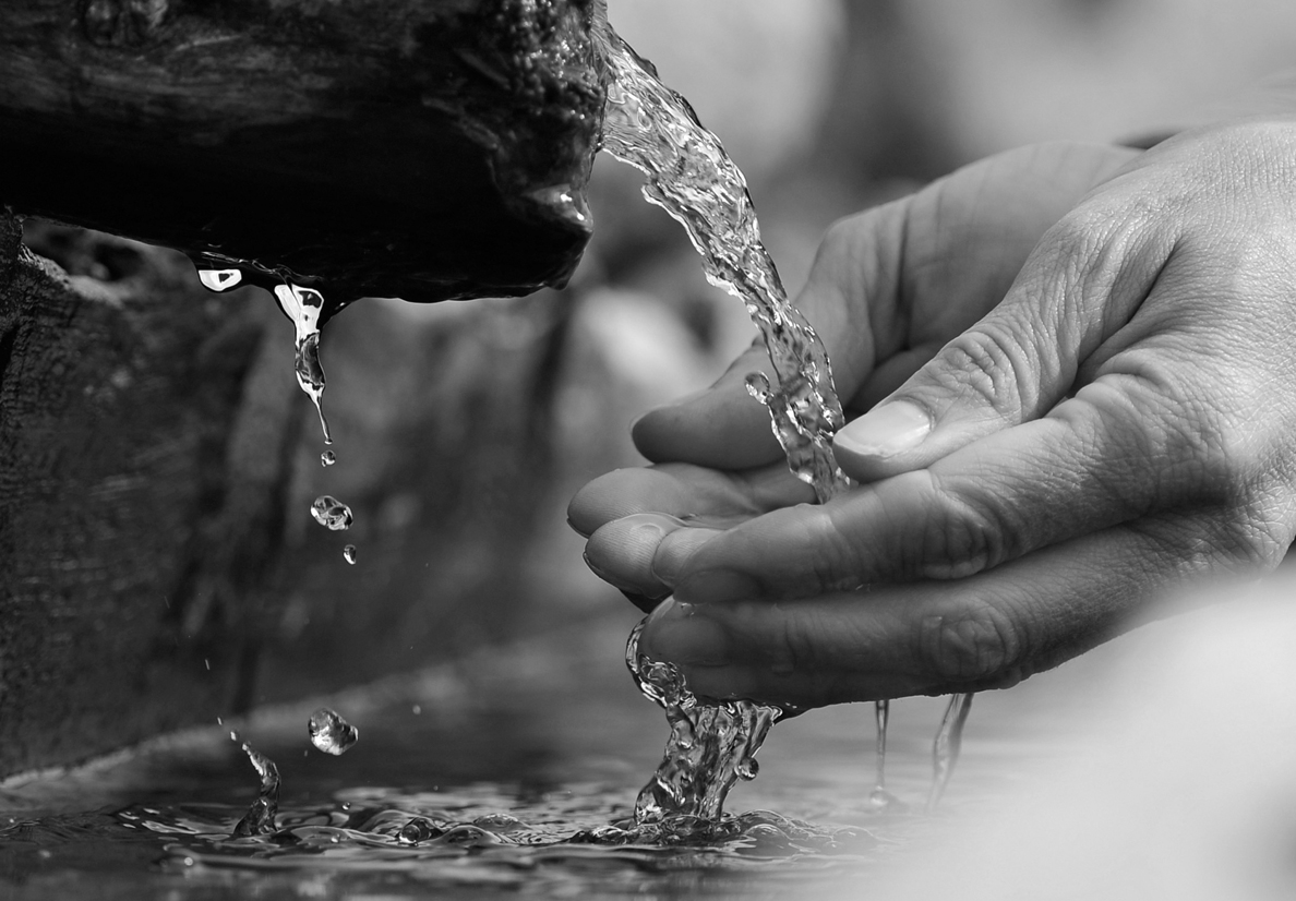 Hands scooping water from a well